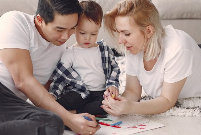 Loving family creating art together, fostering play and connection indoors.