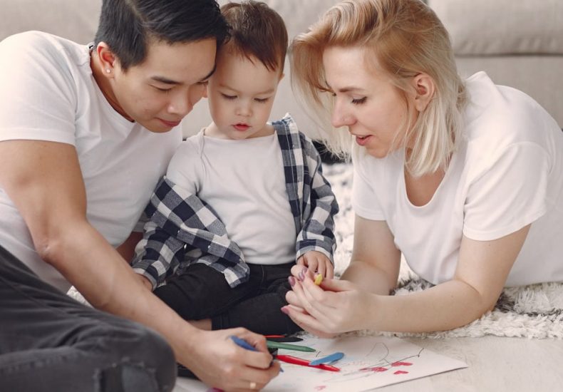 Loving family creating art together, fostering play and connection indoors.